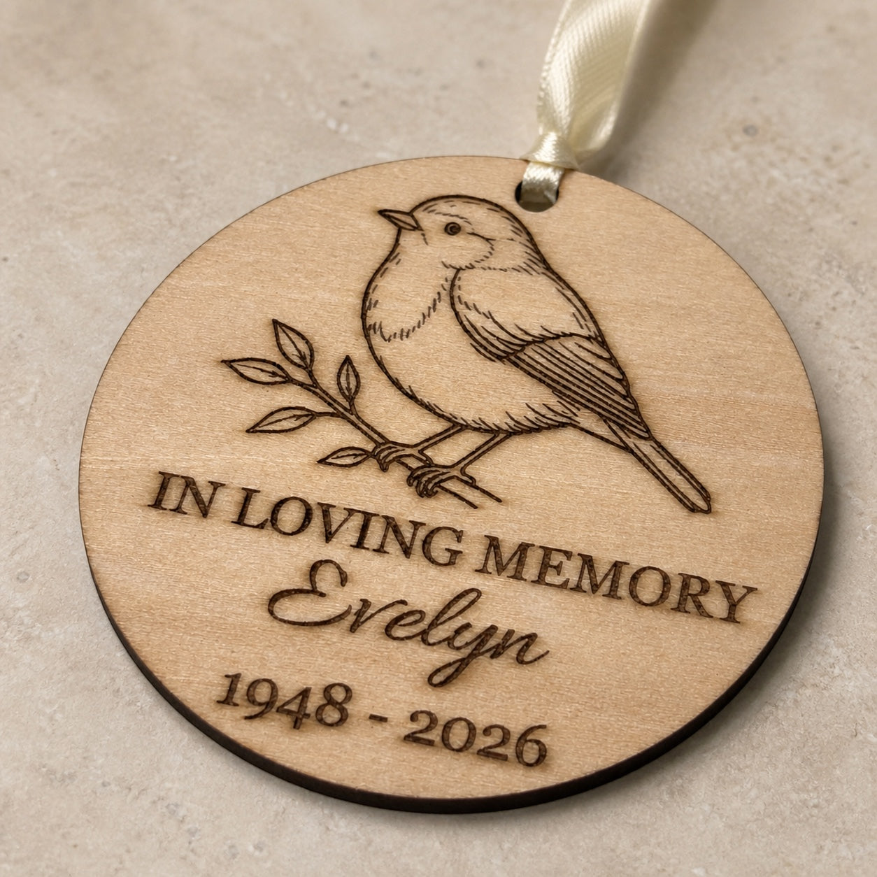 Close detail of laser engraving and birch grain on a robin memorial ornament