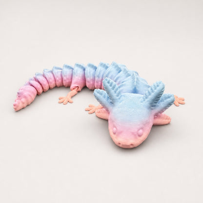 Pastel blue and pink 3D printed articulated axolotl on a pale studio background