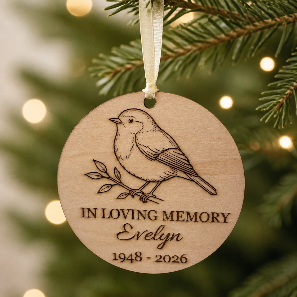 Personalised robin remembrance ornament hanging from an evergreen branch
