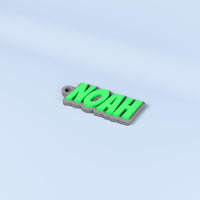 Noah personalised name keyring in Bangers font with green raised text on a dark gray base.