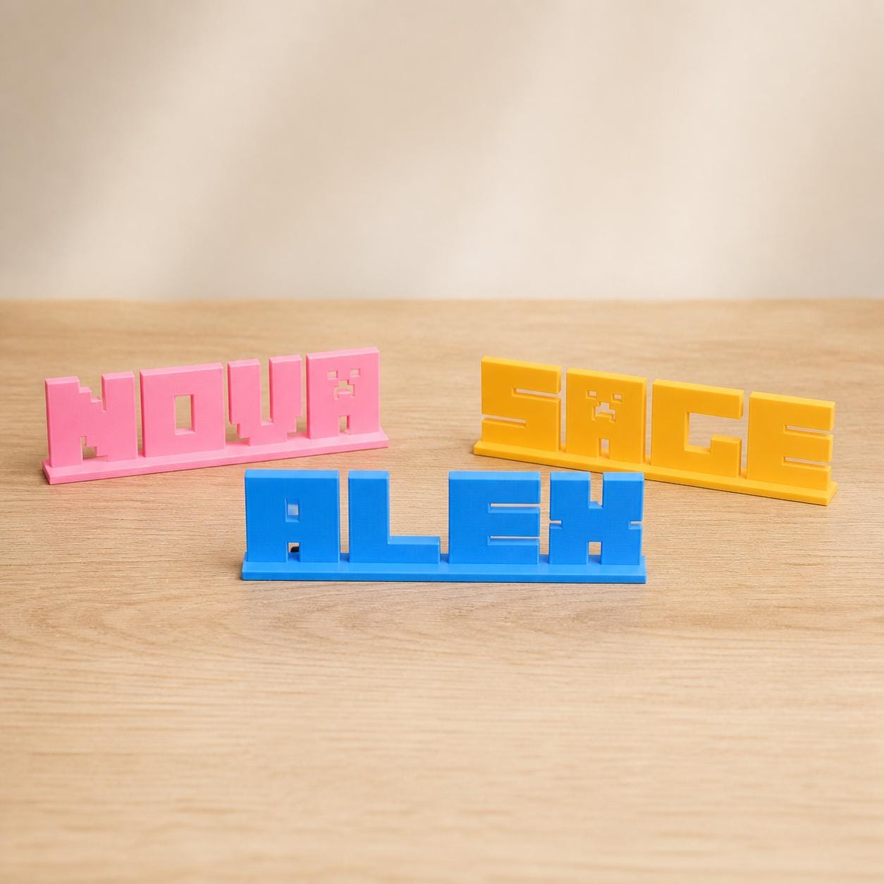 Nova, Alex and Sage block letter personalised PLA nameplates arranged in a warm neutral studio setting.