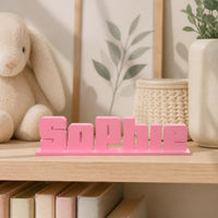 Sophie bold arcade personalised nameplate displayed on a warm neutral nursery shelf.
