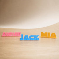 Sophie, Jack and Mia geometric space personalised PLA nameplates arranged in a warm neutral studio setting.