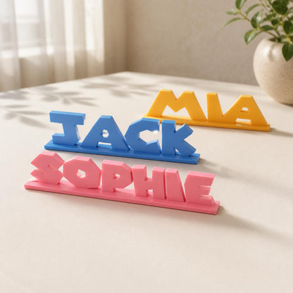 Sophie, Jack and Mia platform adventure personalised PLA nameplates arranged in a warm neutral studio setting.