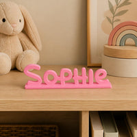 Sophie cartoon style personalised nameplate displayed on a warm neutral nursery shelf.