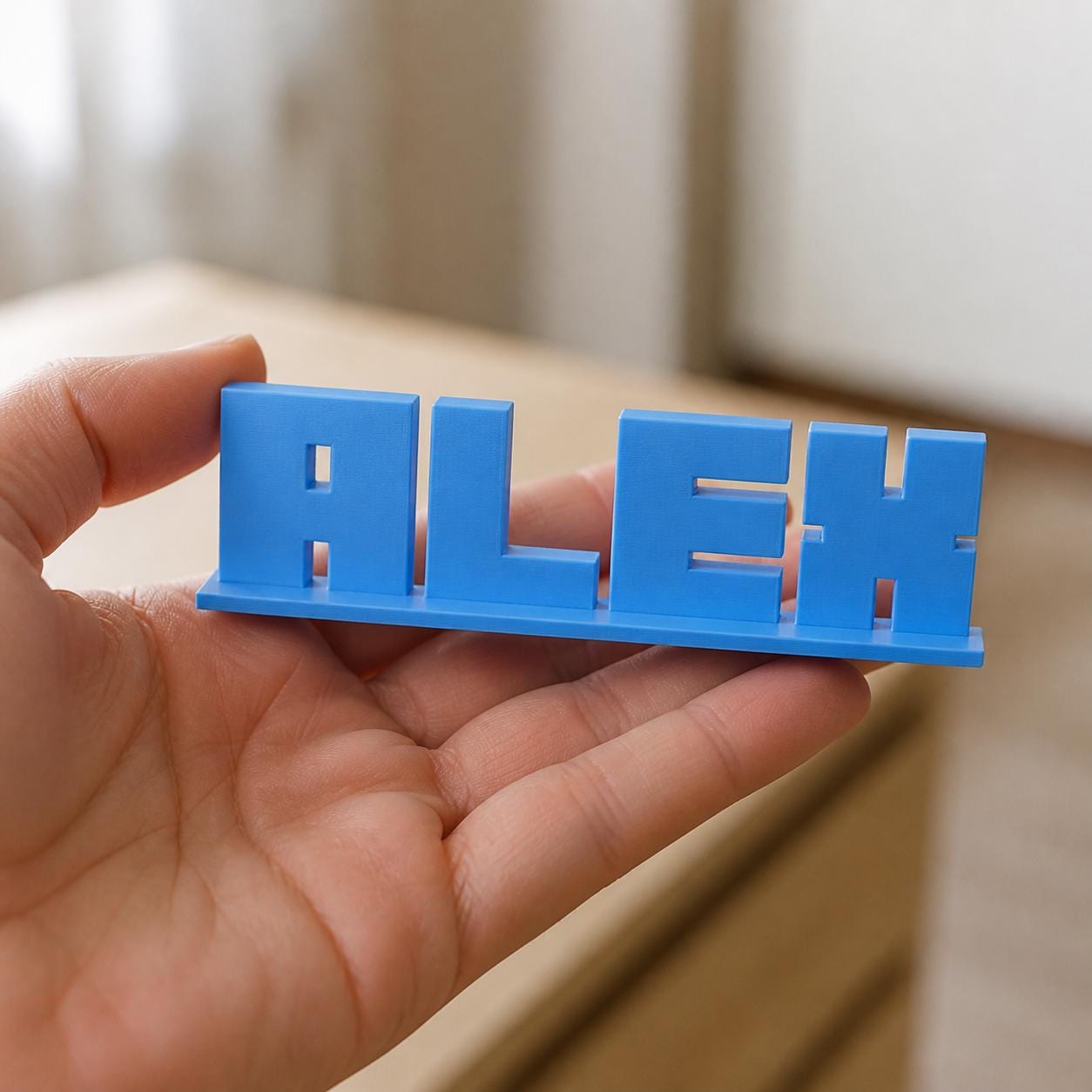 Nova block letter personalised nameplate held in an adult hand to demonstrate scale.