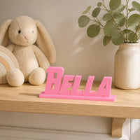 Bella heroic angular personalised nameplate displayed on a warm neutral nursery shelf.