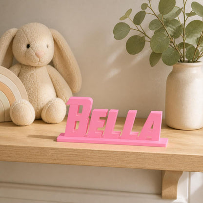 Bella heroic angular personalised nameplate displayed on a warm neutral nursery shelf.