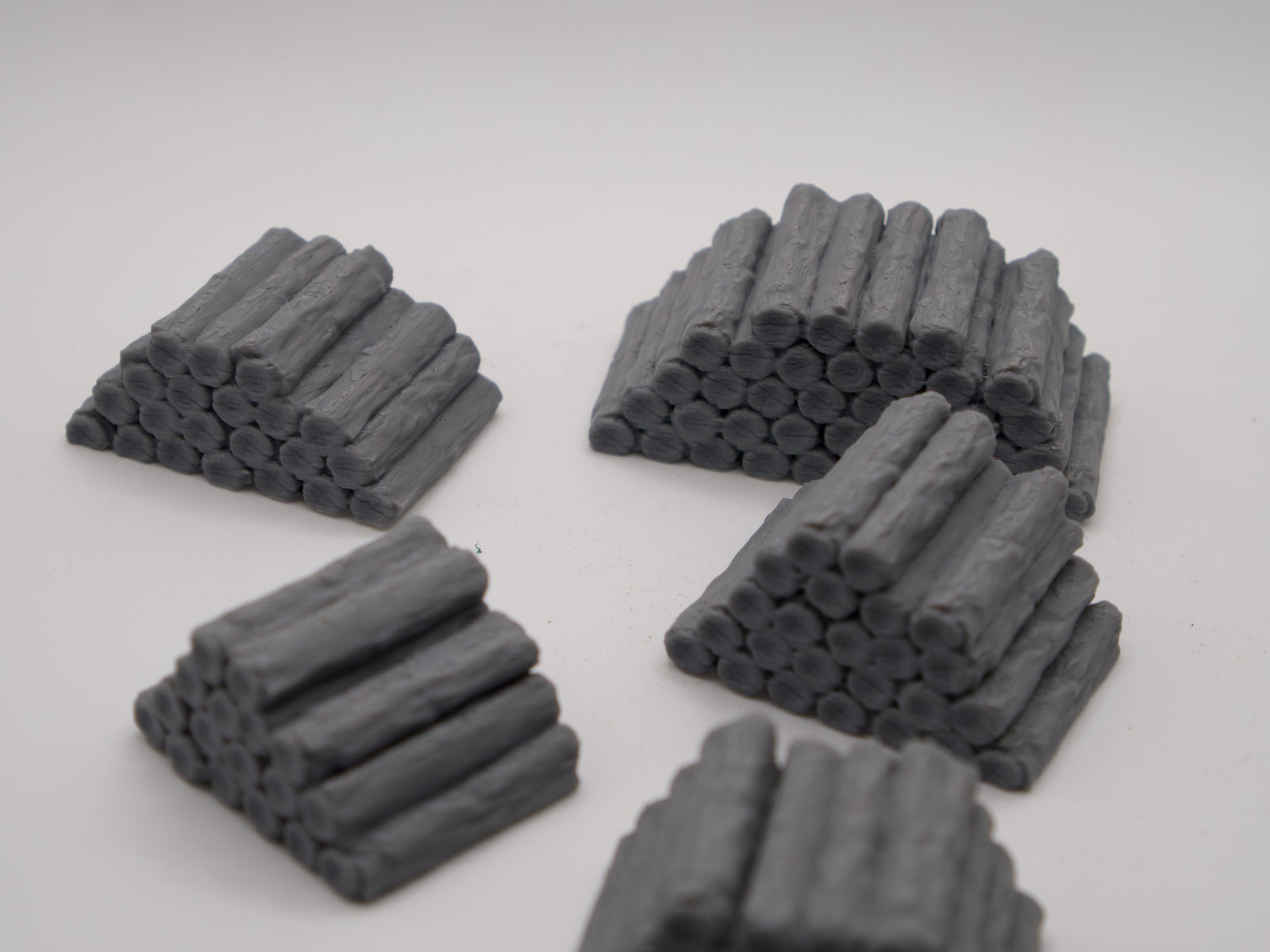 Five 3D printed log pile terrain pieces on a plain backdrop